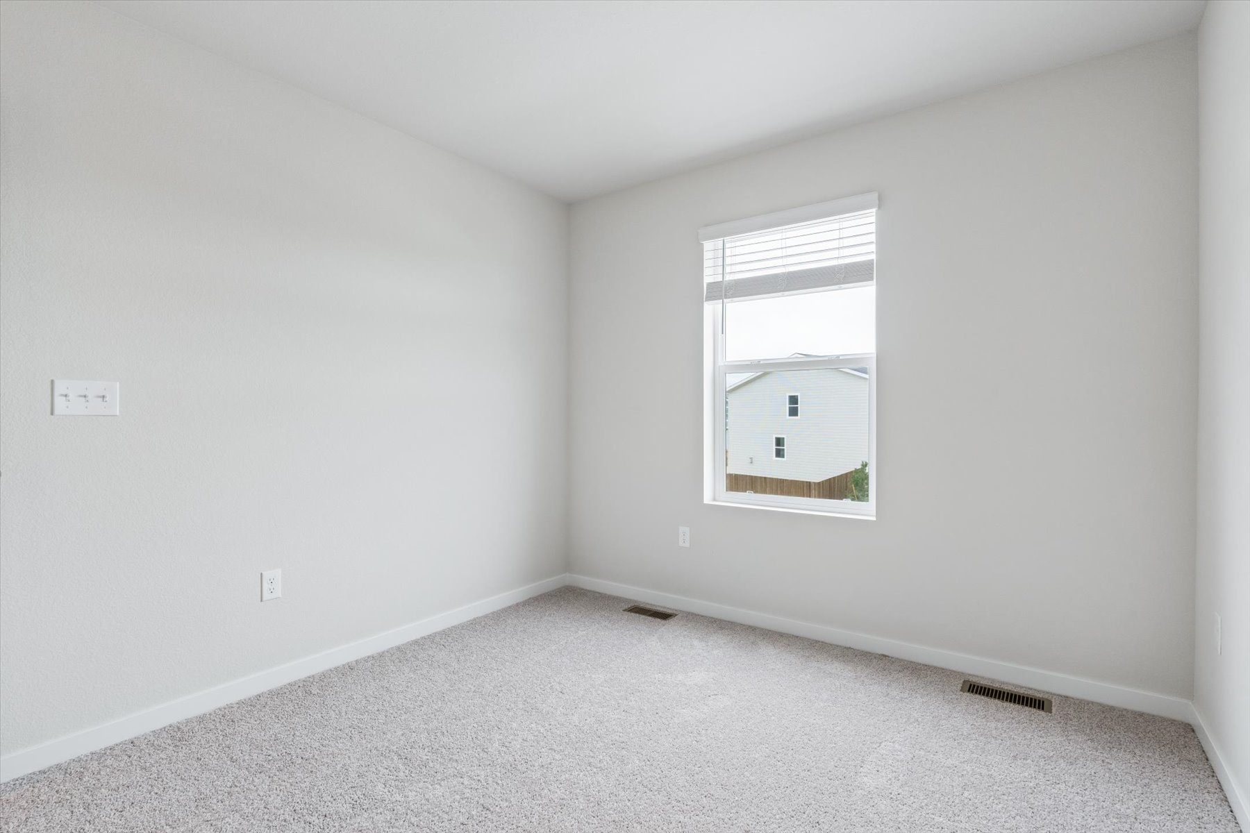 A room with a window and a white wall.