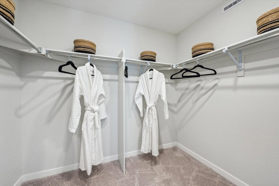A white coat rack with a white robe and a basket on it.