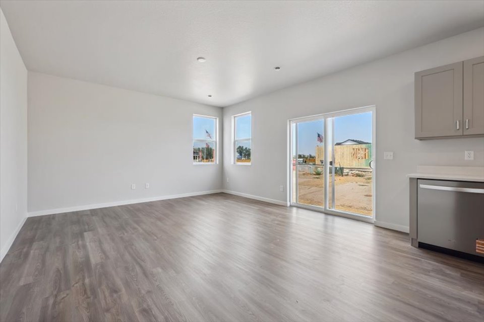 A large empty room with a wood floor and a large window.
