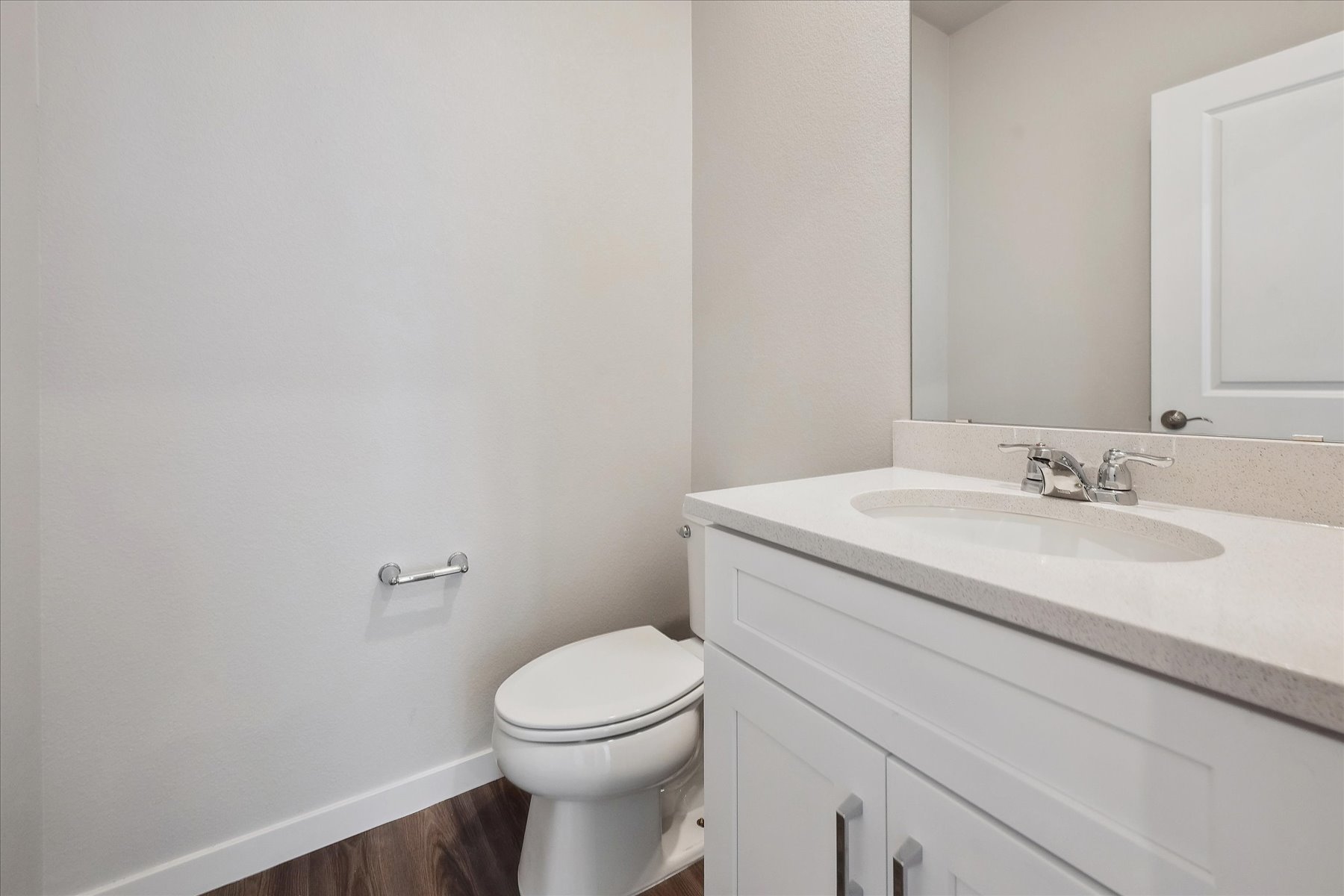 A bathroom with a sink toilet and mirror.