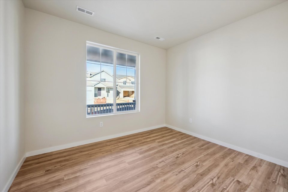 A room with a wood floor and a window with a view of a city.