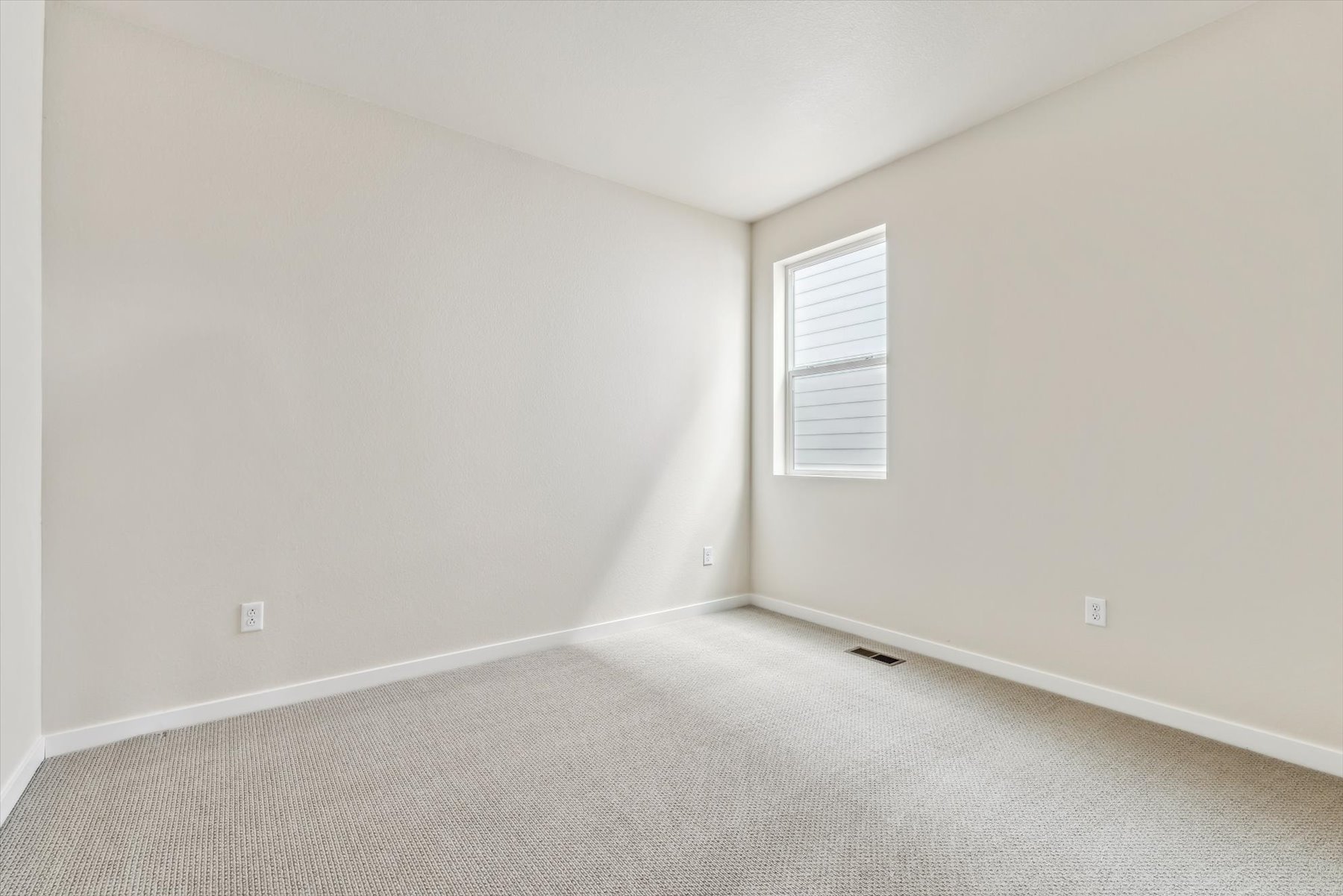 A room with a white wall and a window.