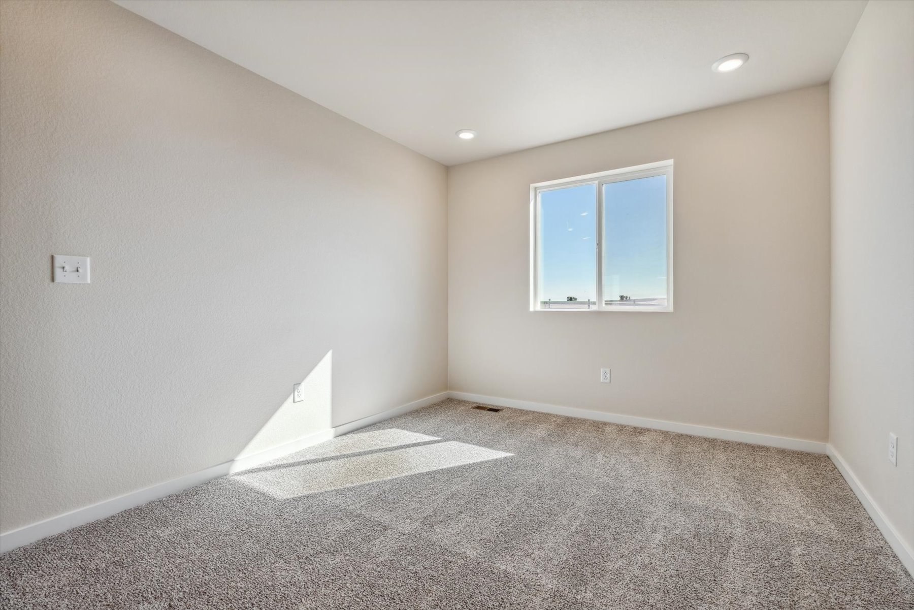 A room with a window and a rug.