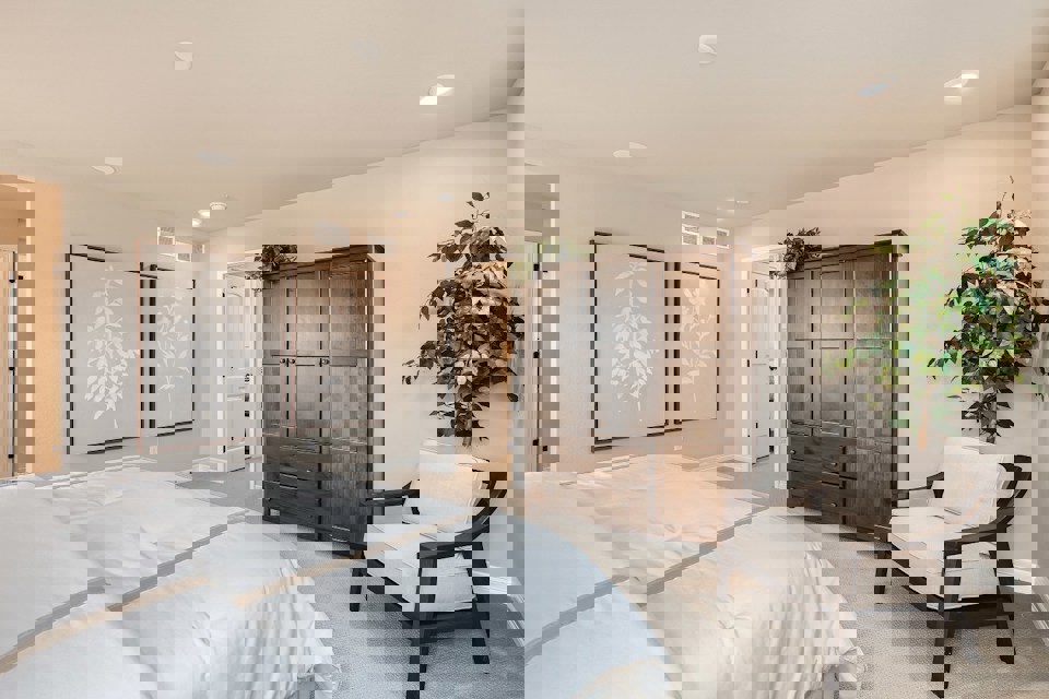 A bedroom with a bed and a chair.