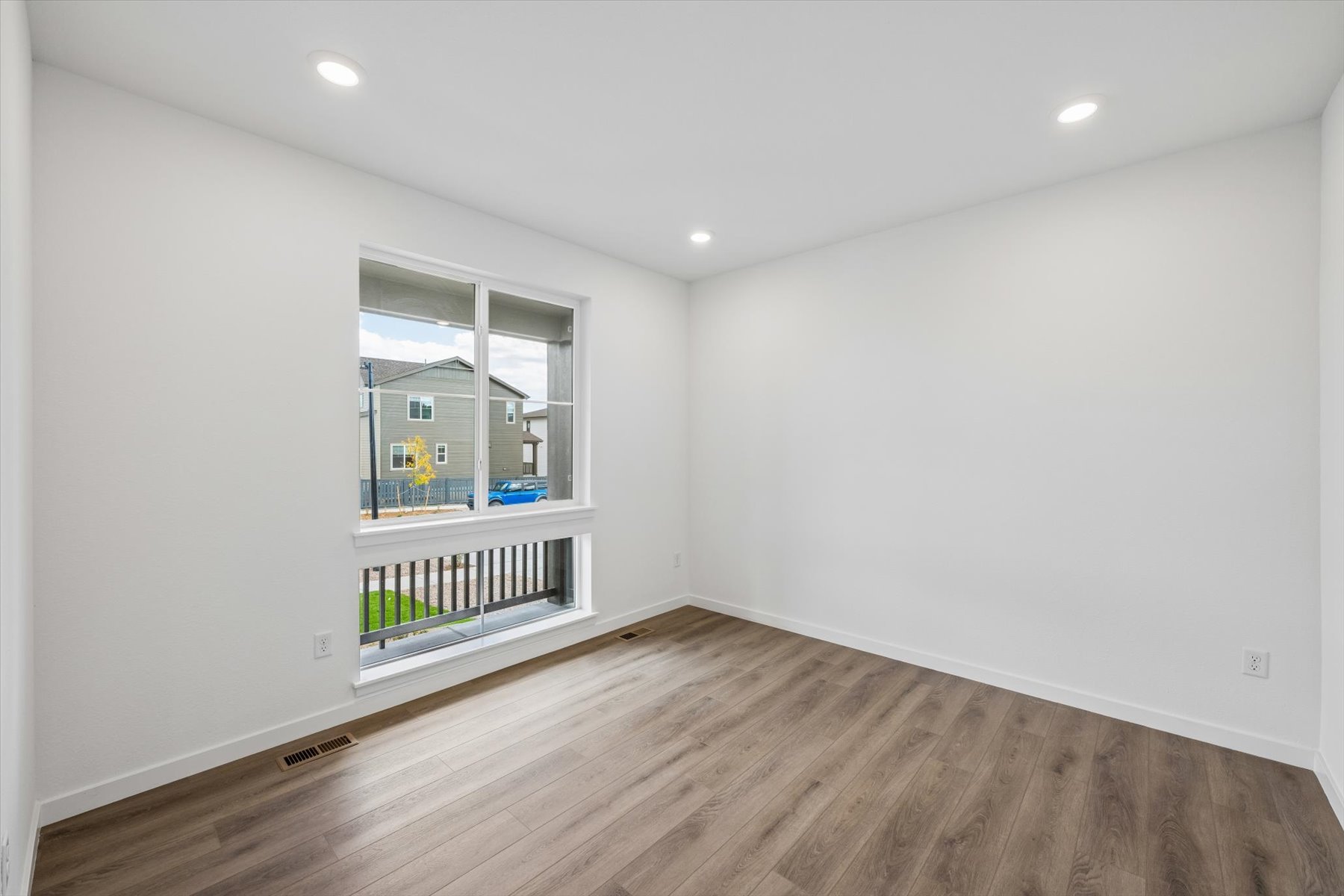 A room with a window and a wood floor.