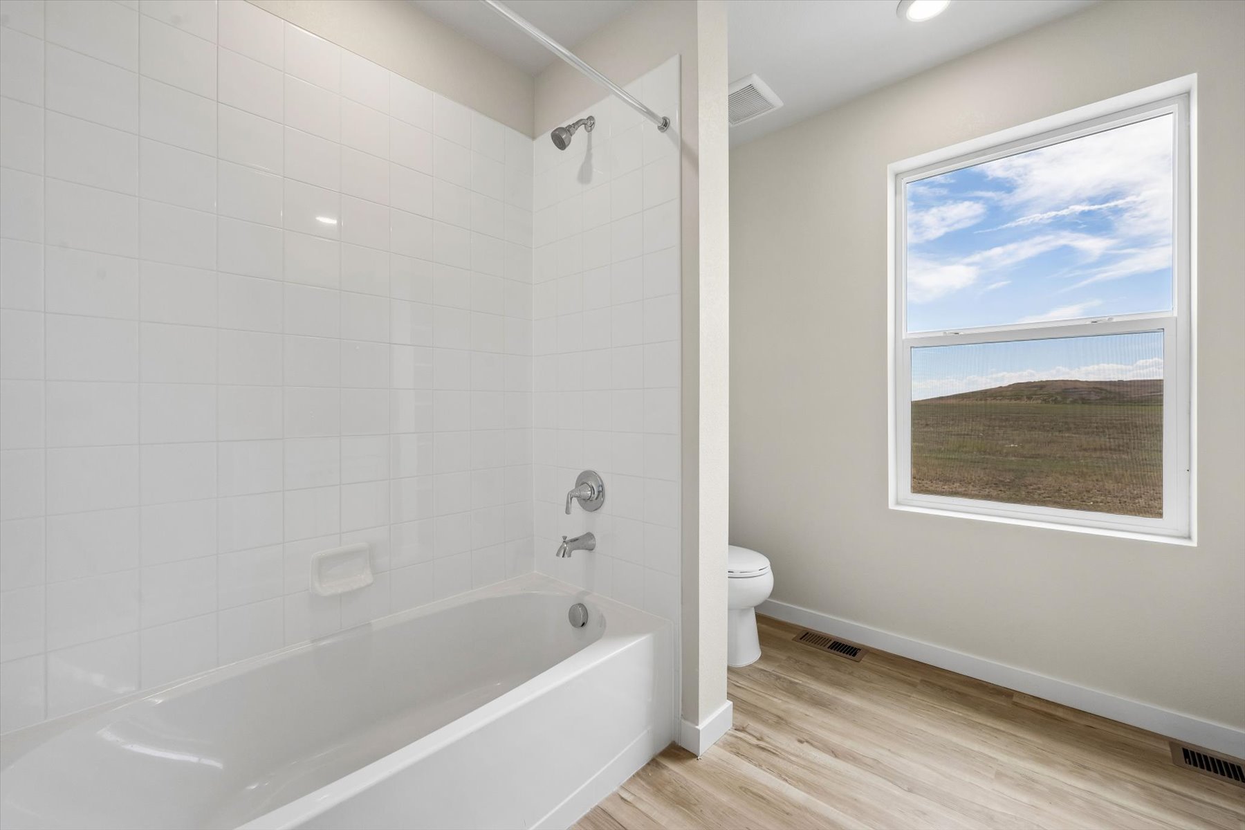 A bathroom with a tub toilet and a window.
