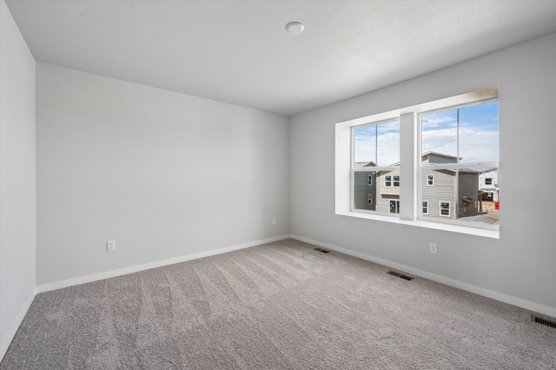 A room with a window and a white wall.