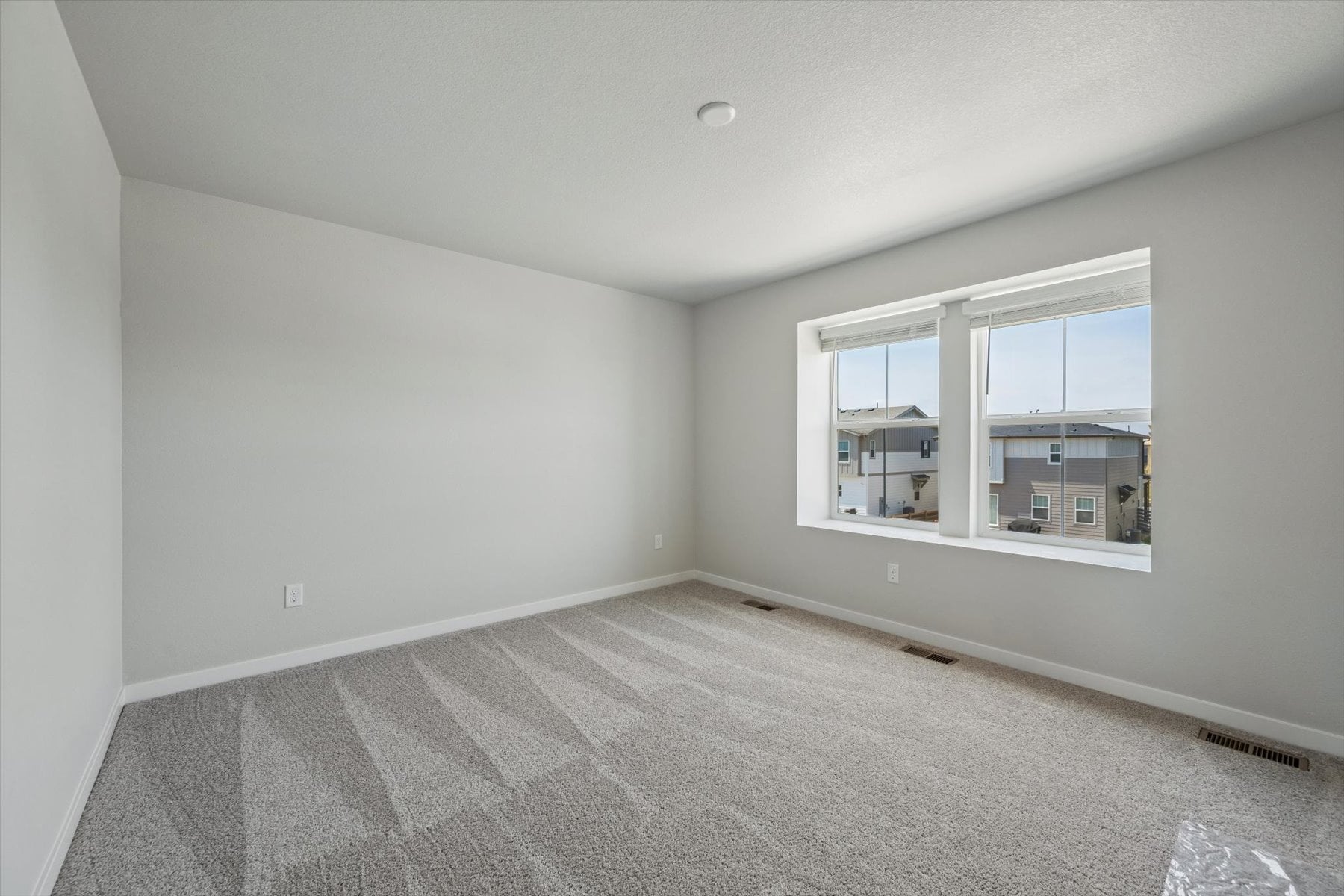 A room with a window and a white wall.