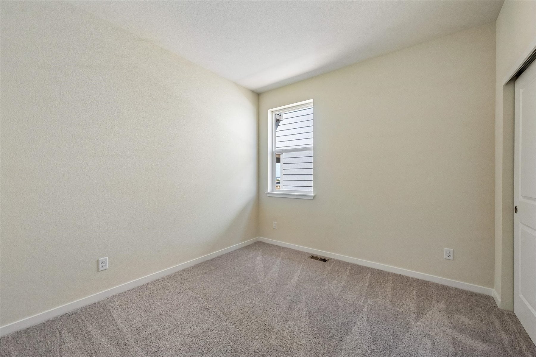 A room with a carpet and a window.