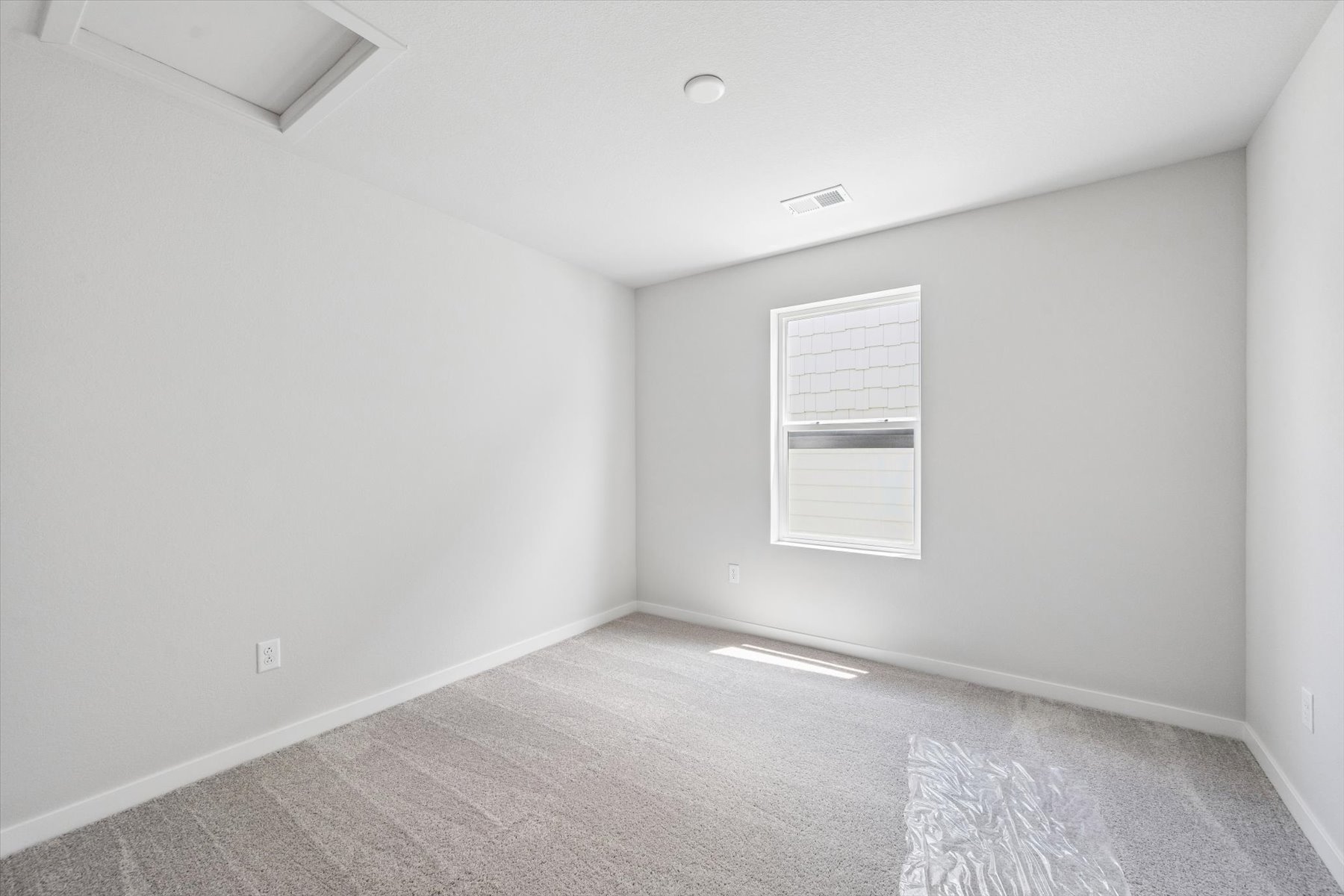 A room with a white wall and a window.