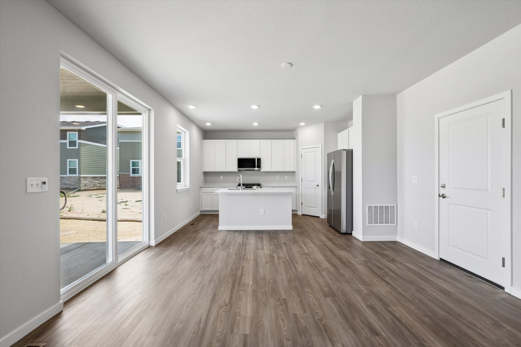 A large white room with a wood floor and a glass door.