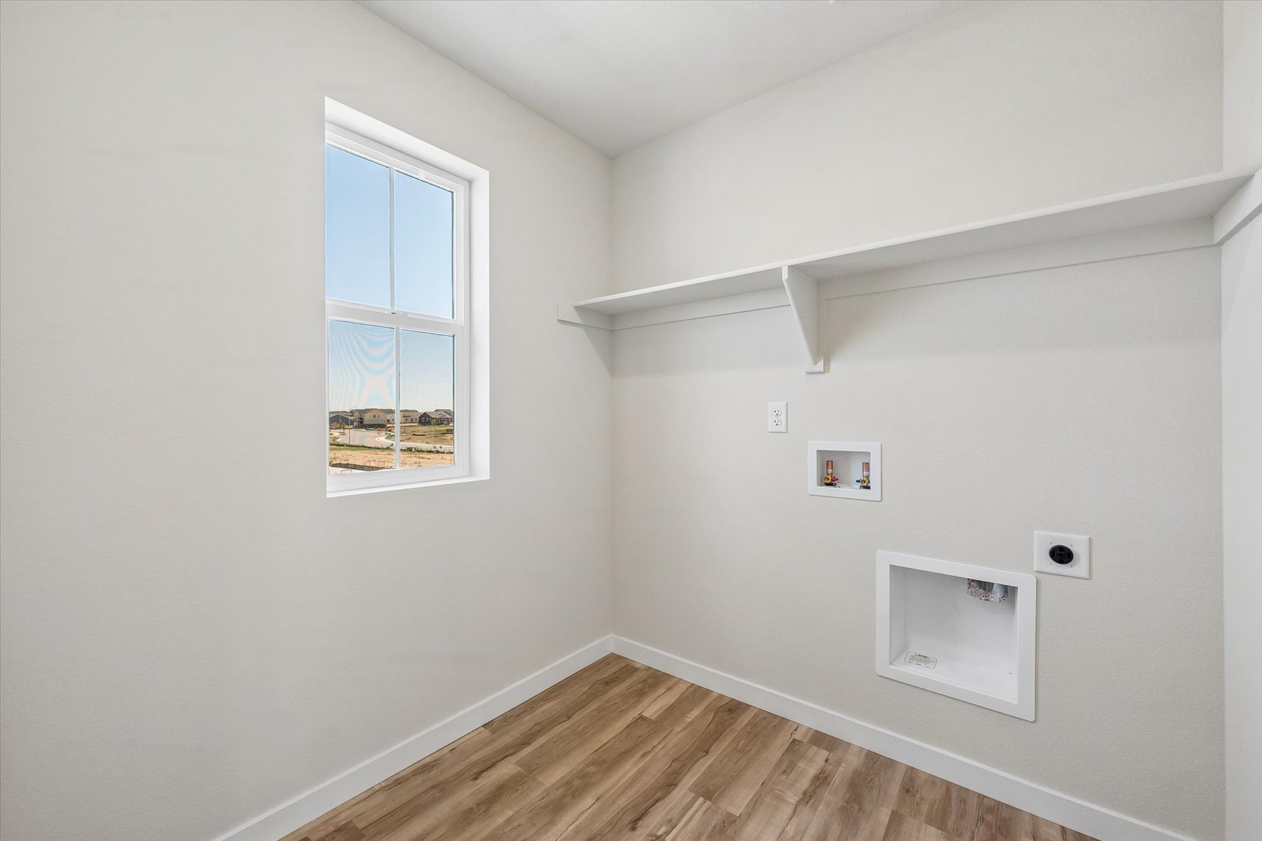 A room with a window and a wood floor.