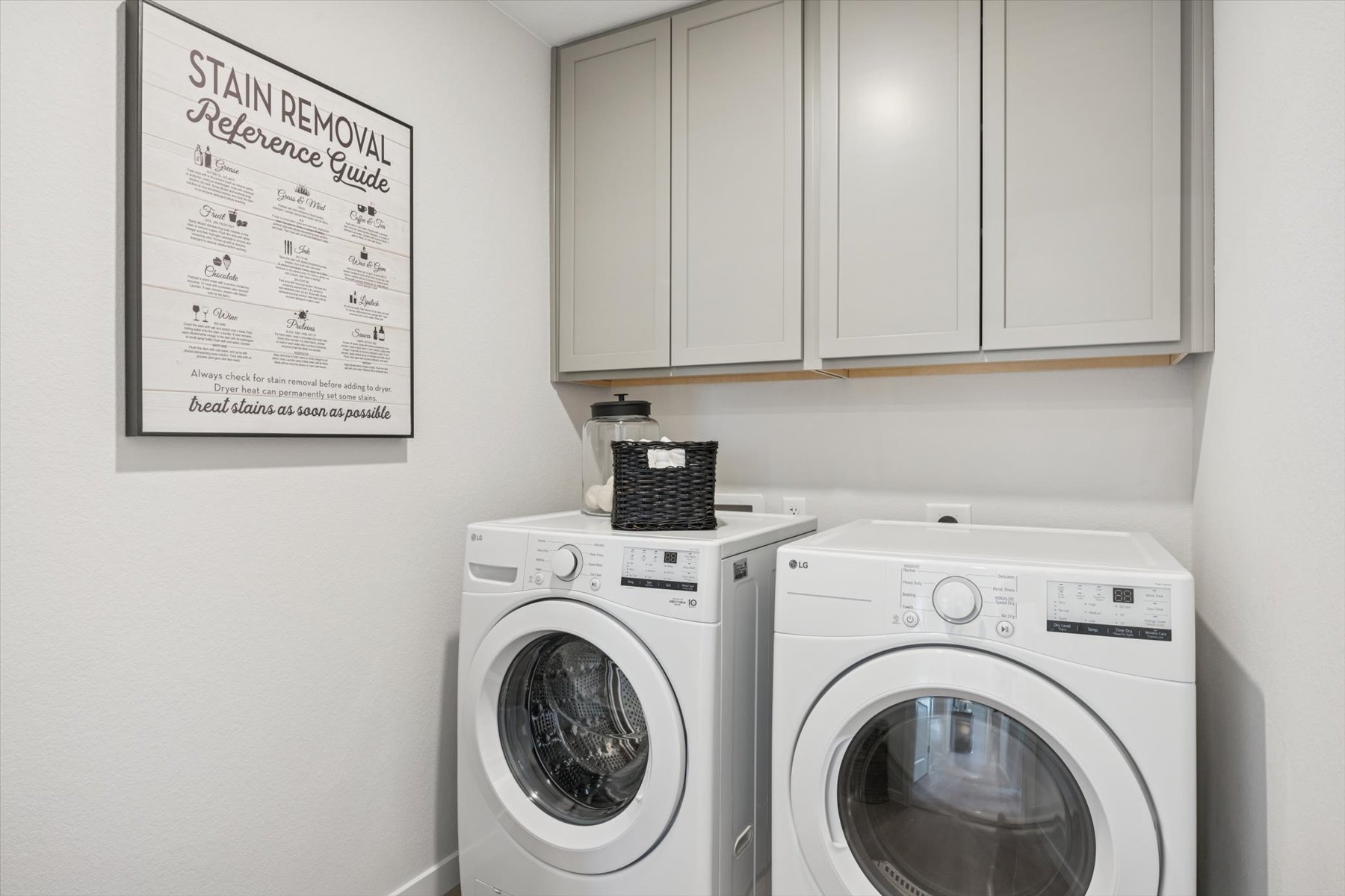 A white washer and dryer in a room with white cabinets.