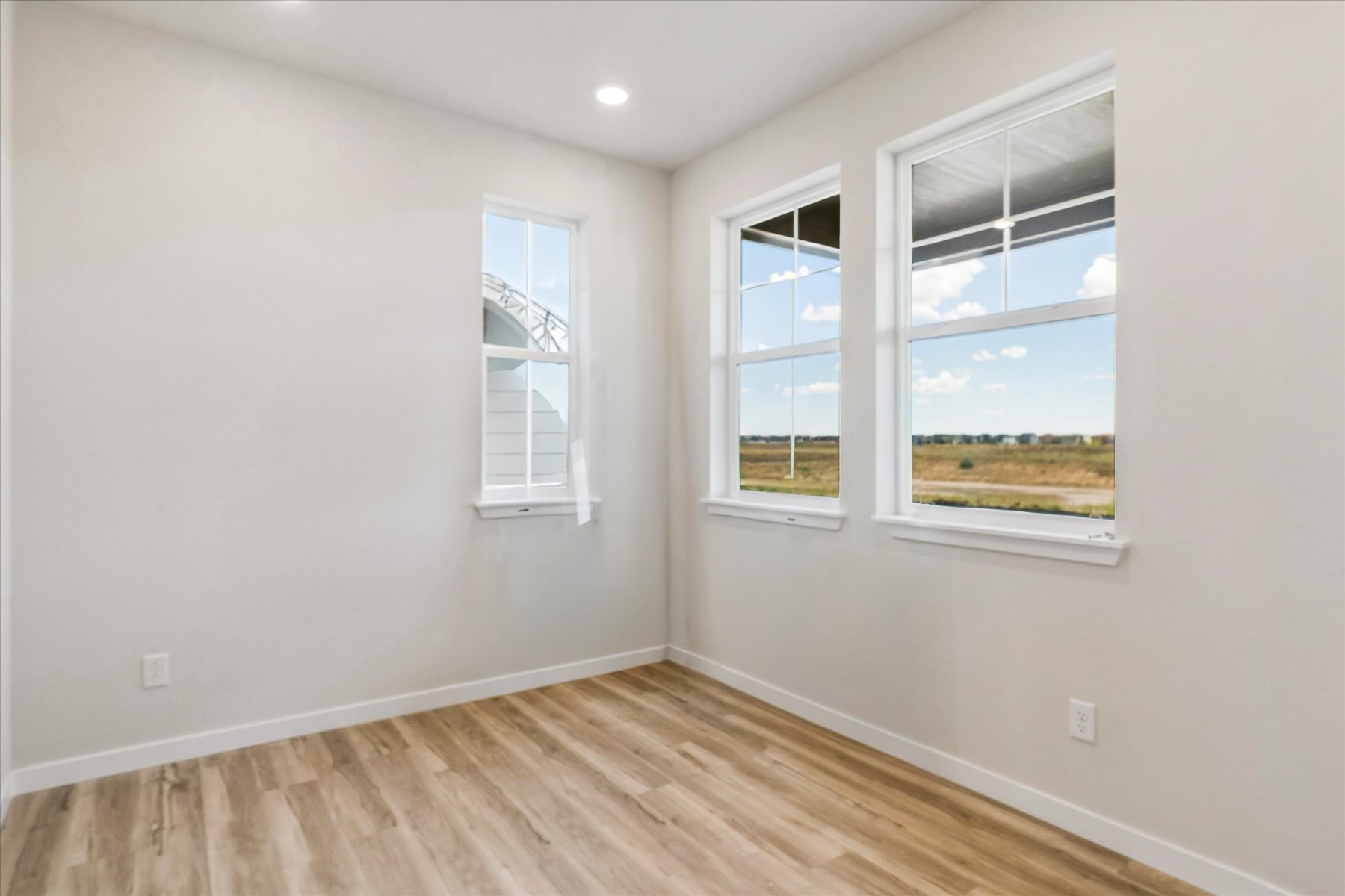 A room with windows and a wood floor.