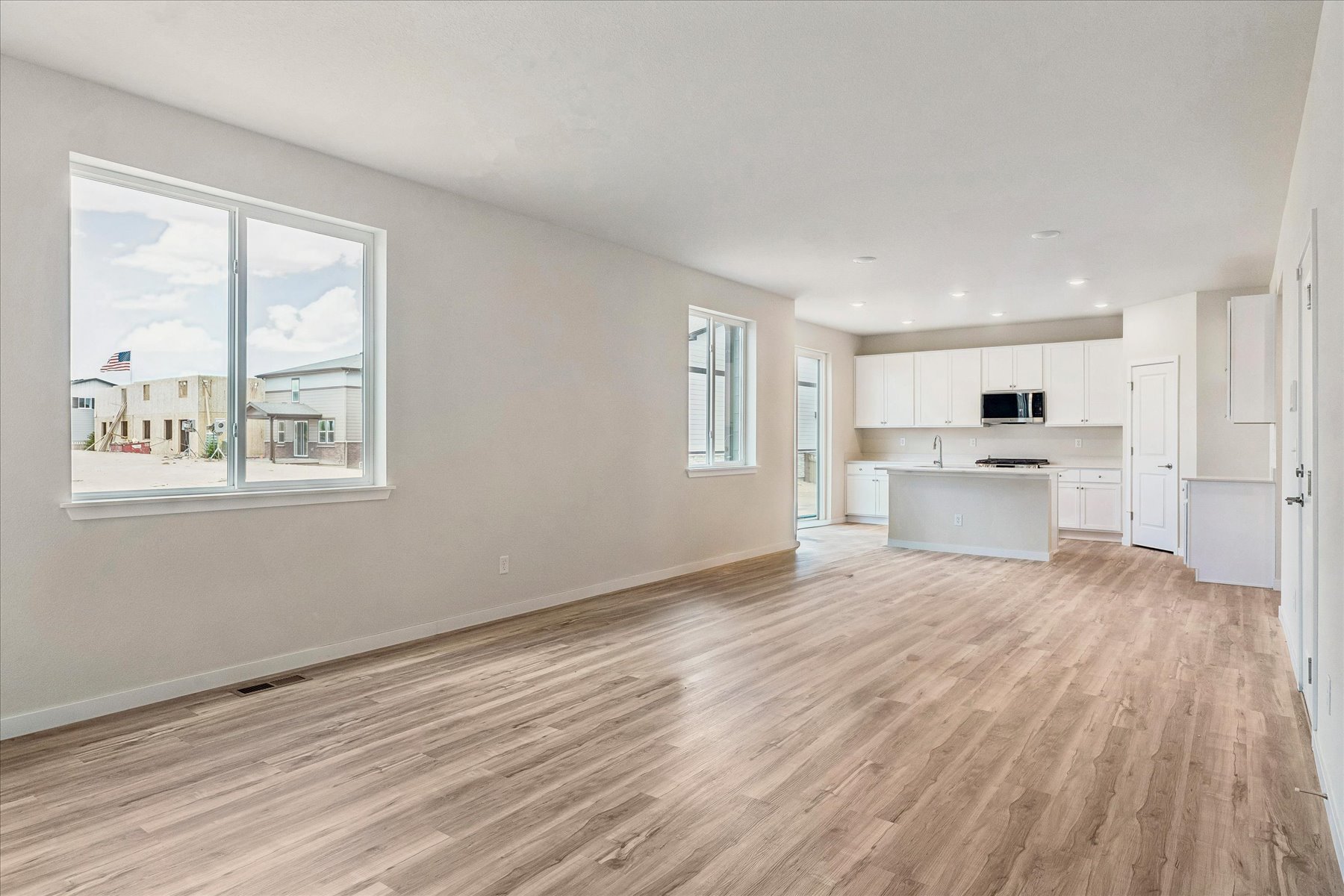 A large empty room with a wood floor and a window.