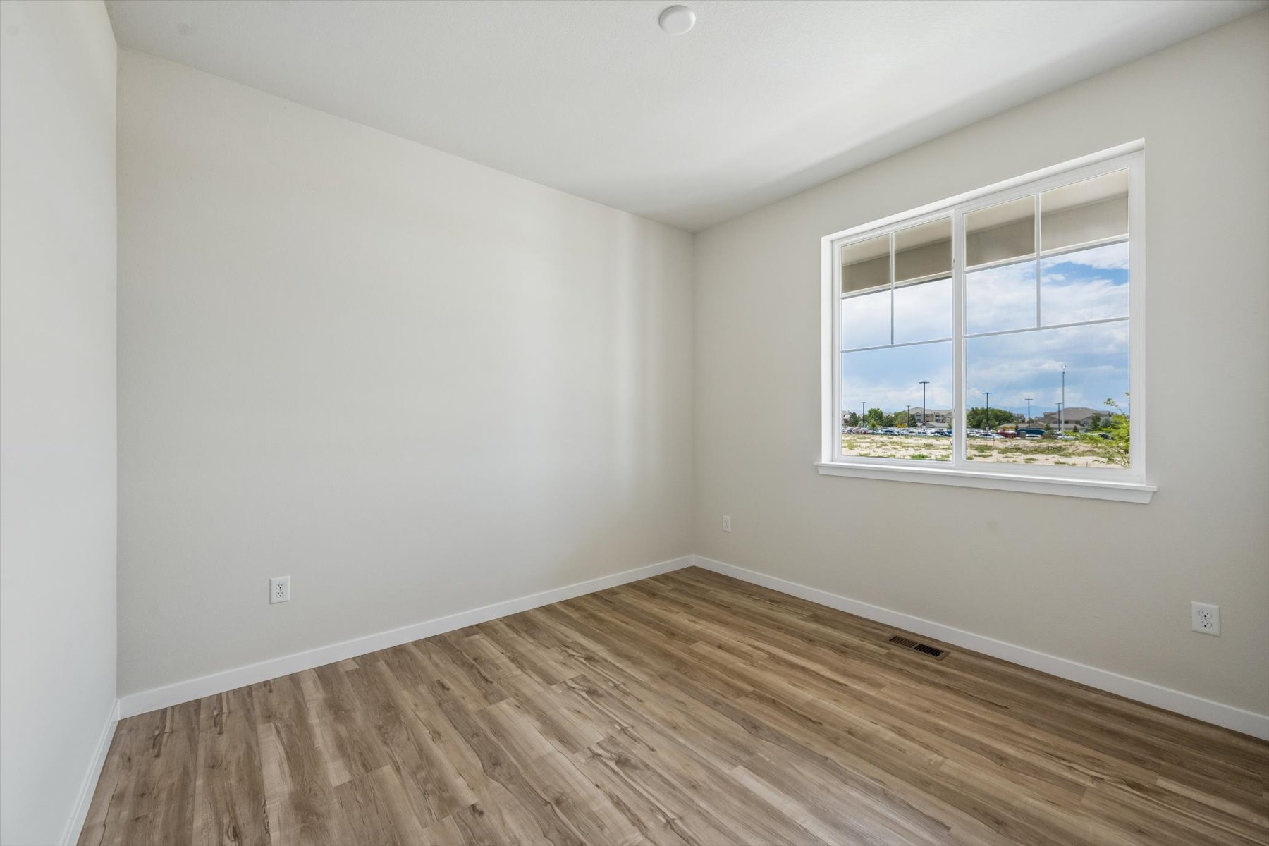 A room with a wood floor and a window with a view of the ocean.