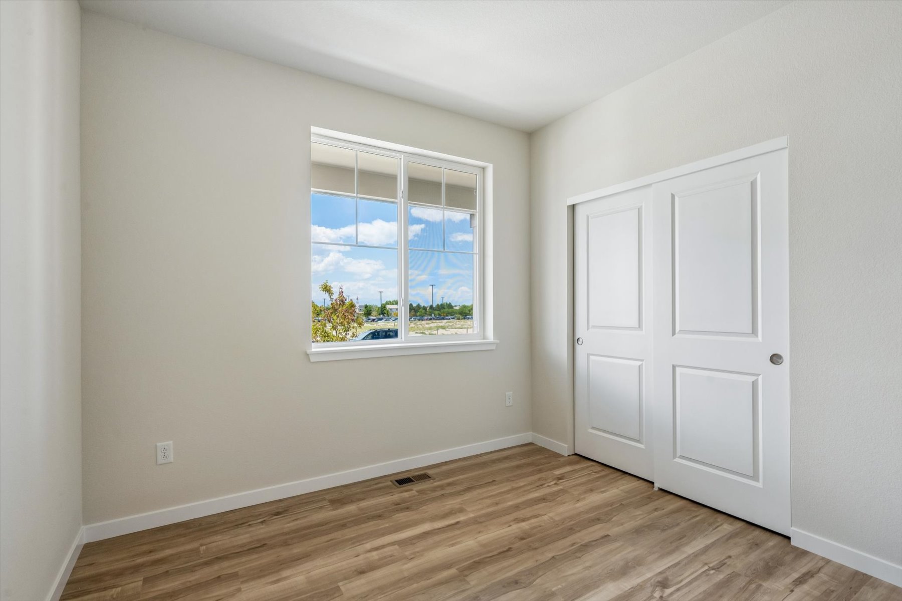 A room with a window and a wood floor.