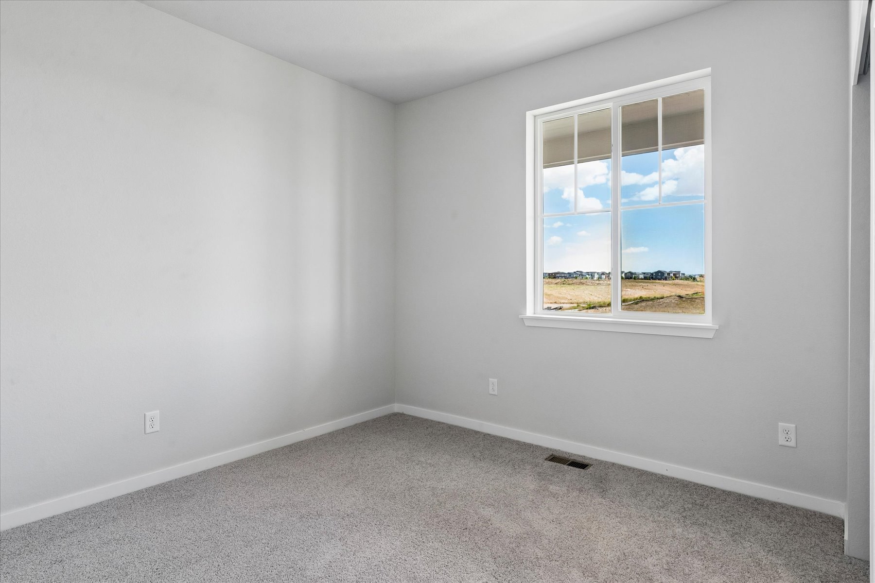 A room with a window and a white wall.