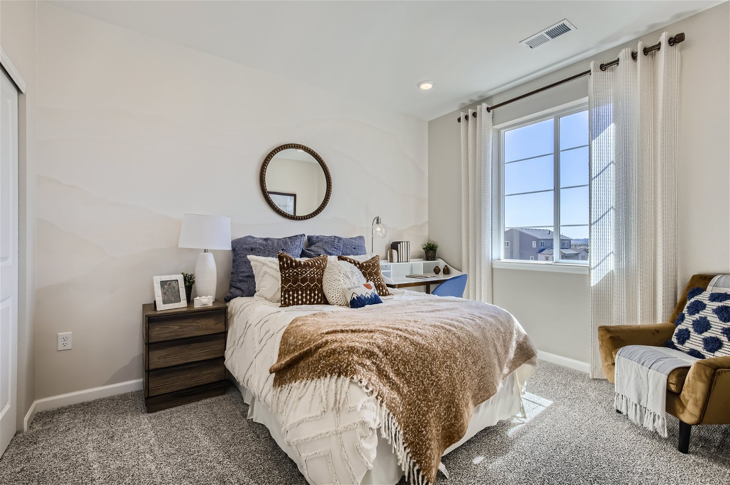 A bedroom with a bed and a mirror.