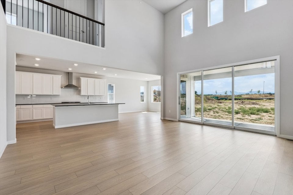 A large white room with a large window and a wood floor.