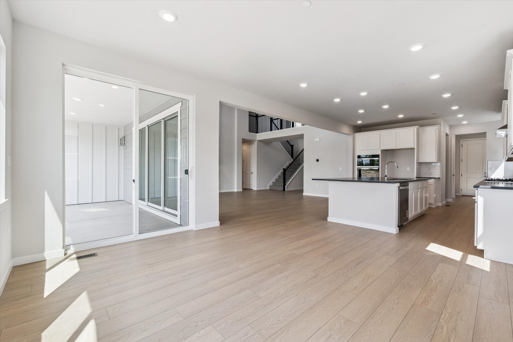 A large white kitchen with a wood floor.