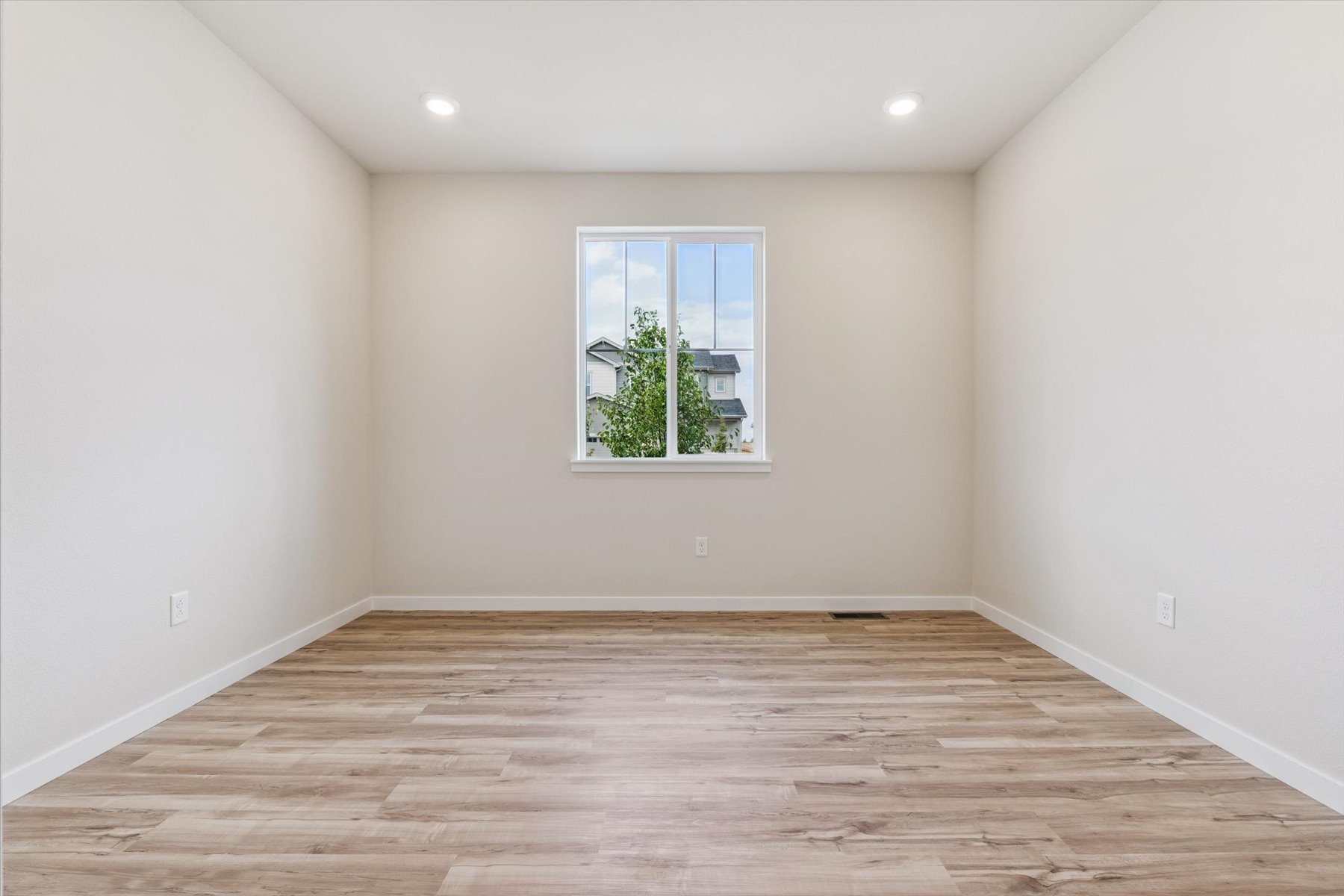 A room with a window and a wood floor.