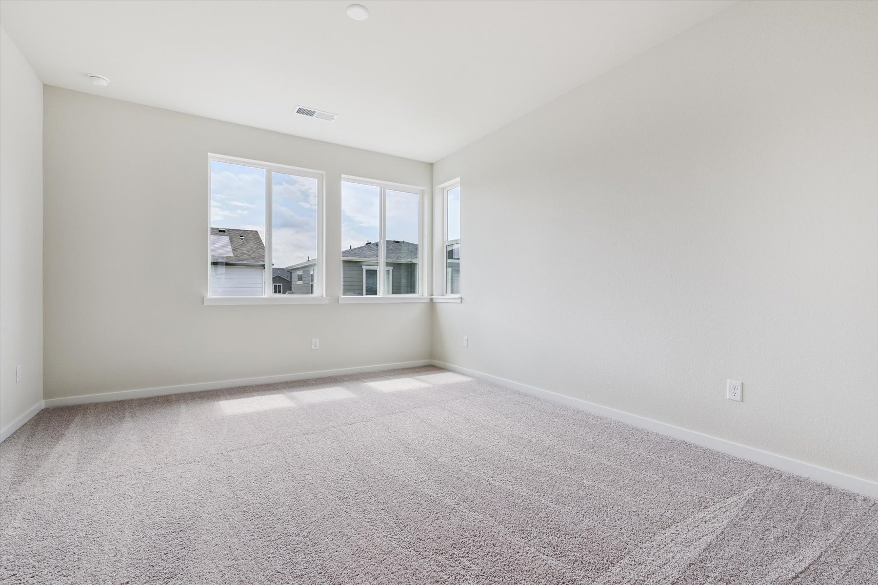 A room with a white carpet and windows.