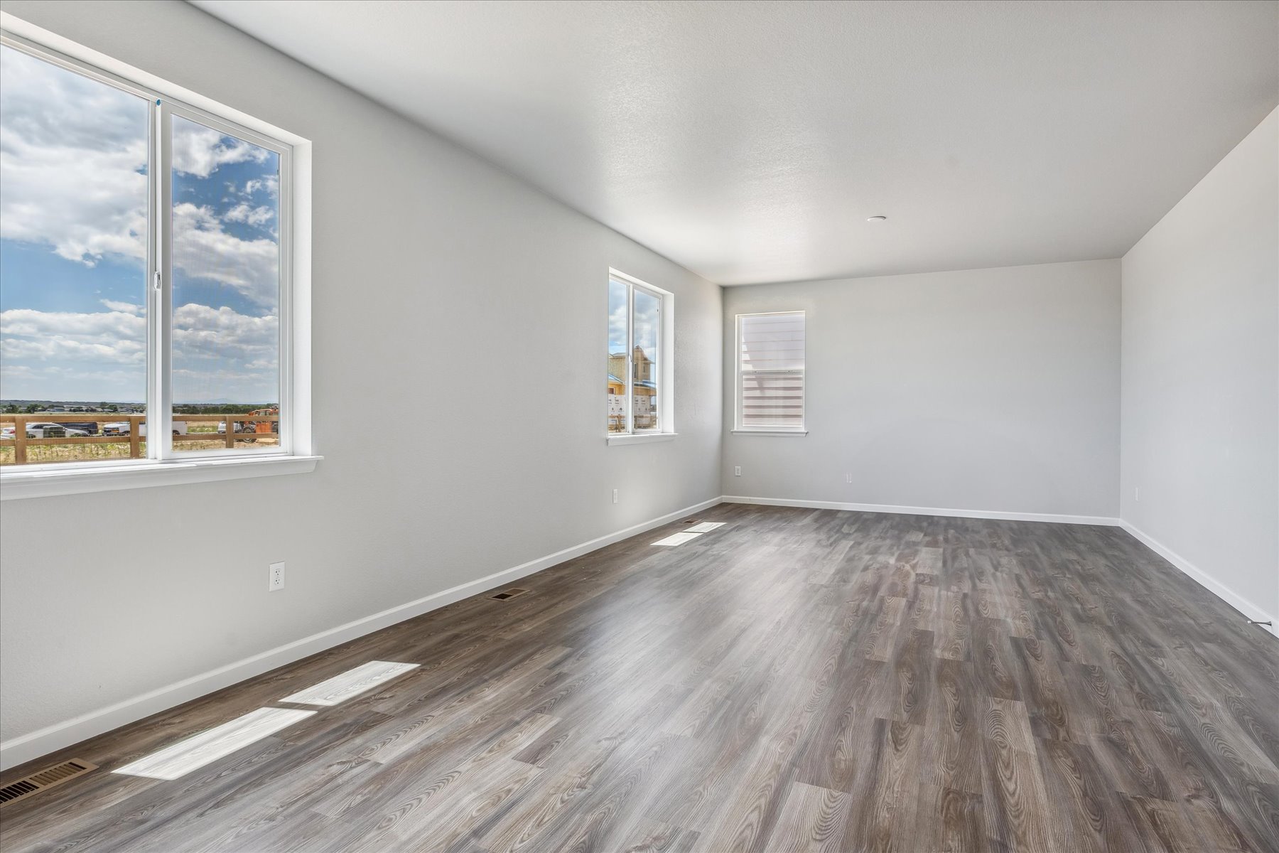 A room with a wood floor and a window with a view of the ocean.