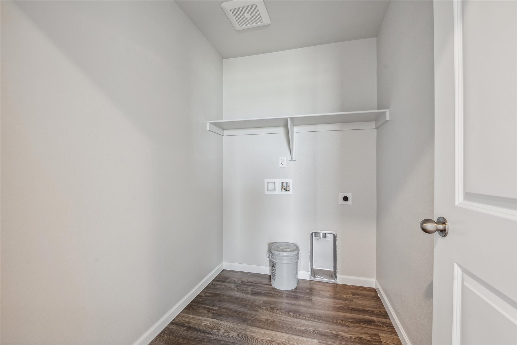 A room with a shelf and a trash can.