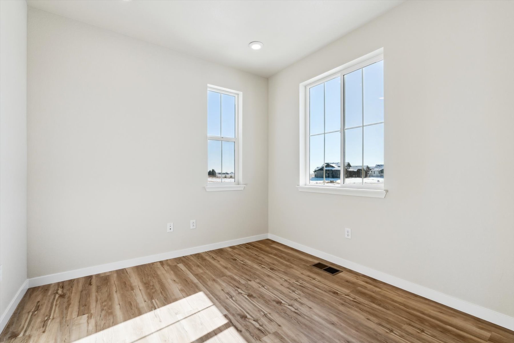 A room with a wood floor and windows.