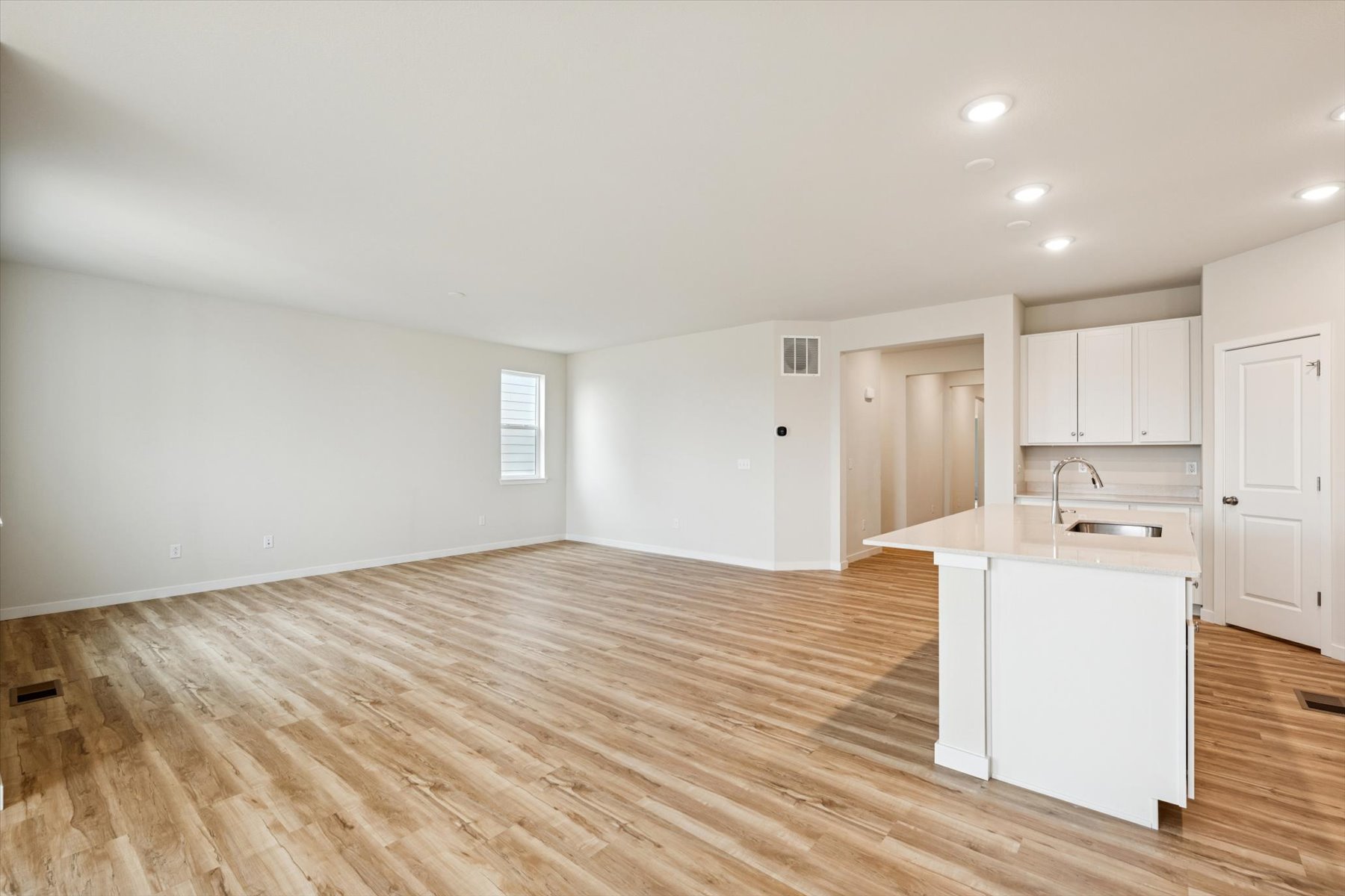 A room with white cabinets and a wood floor.