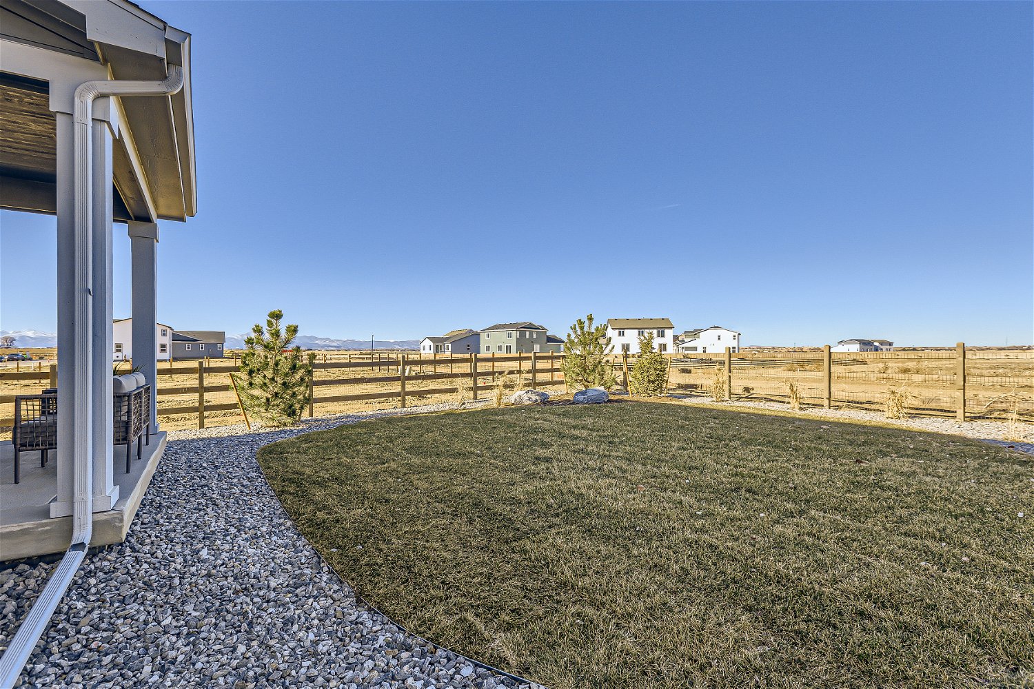 A grassy area with a fence and buildings in the background.