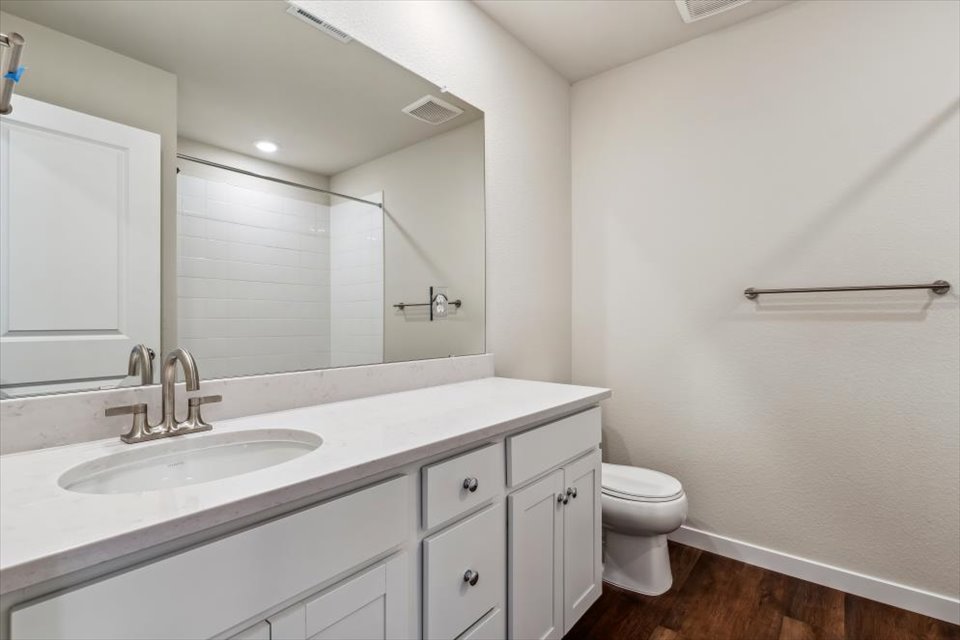 A bathroom with a sink toilet and mirror.