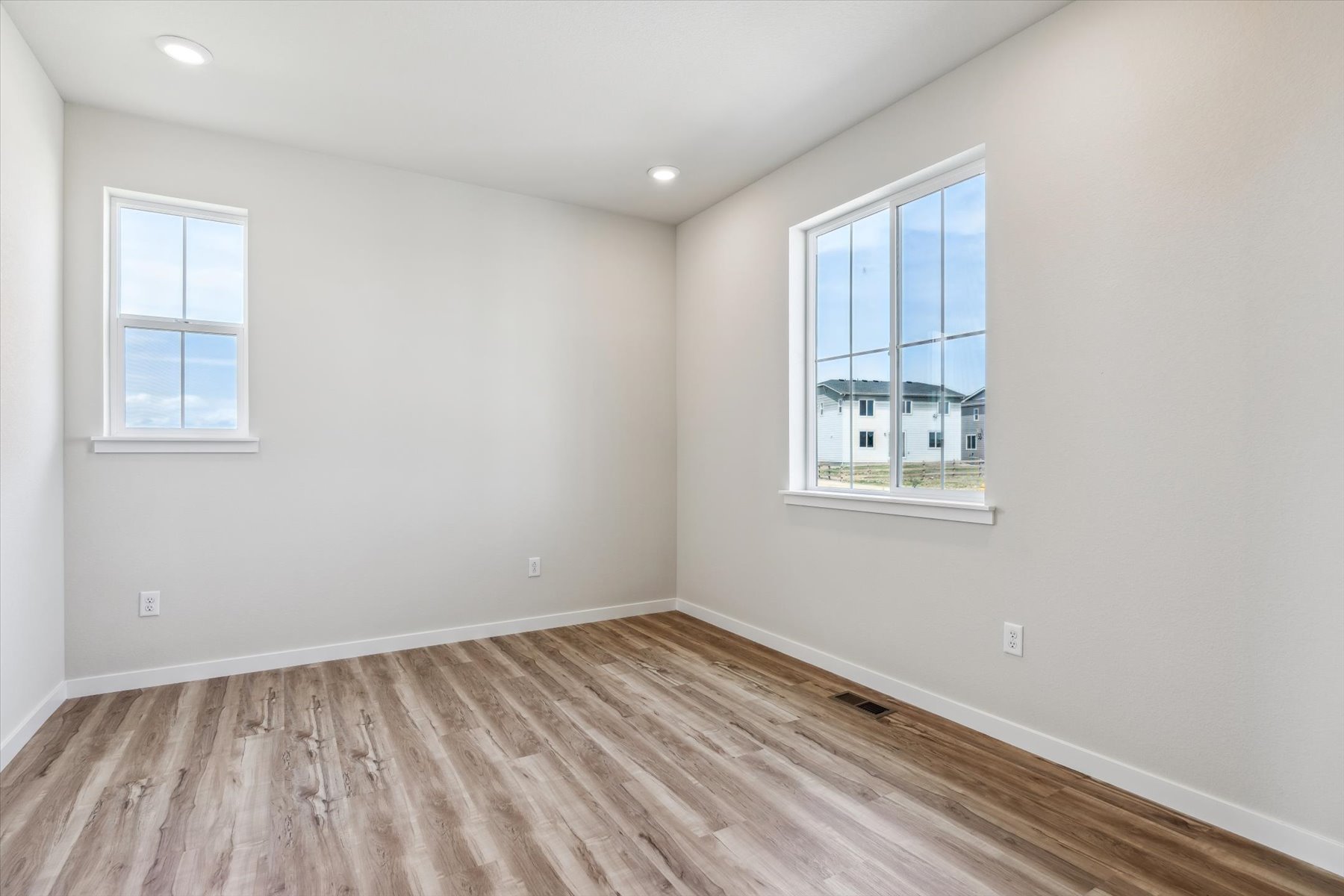 A room with a wood floor and windows.