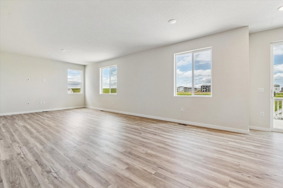 A room with a wood floor and a wood floor with a few framed pictures on the wall.