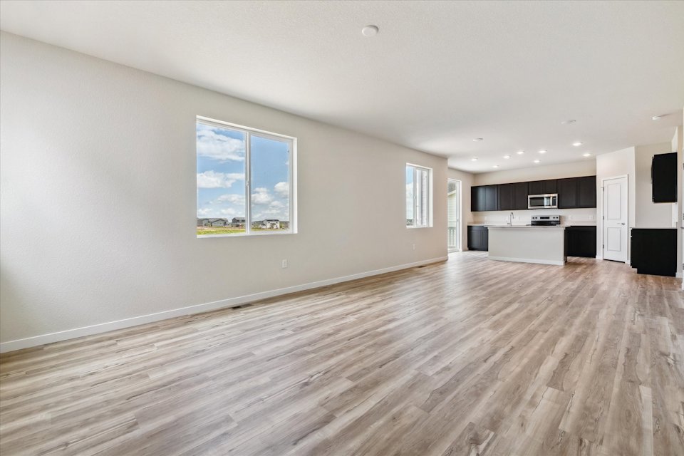 A large empty room with a wood floor and a large window.