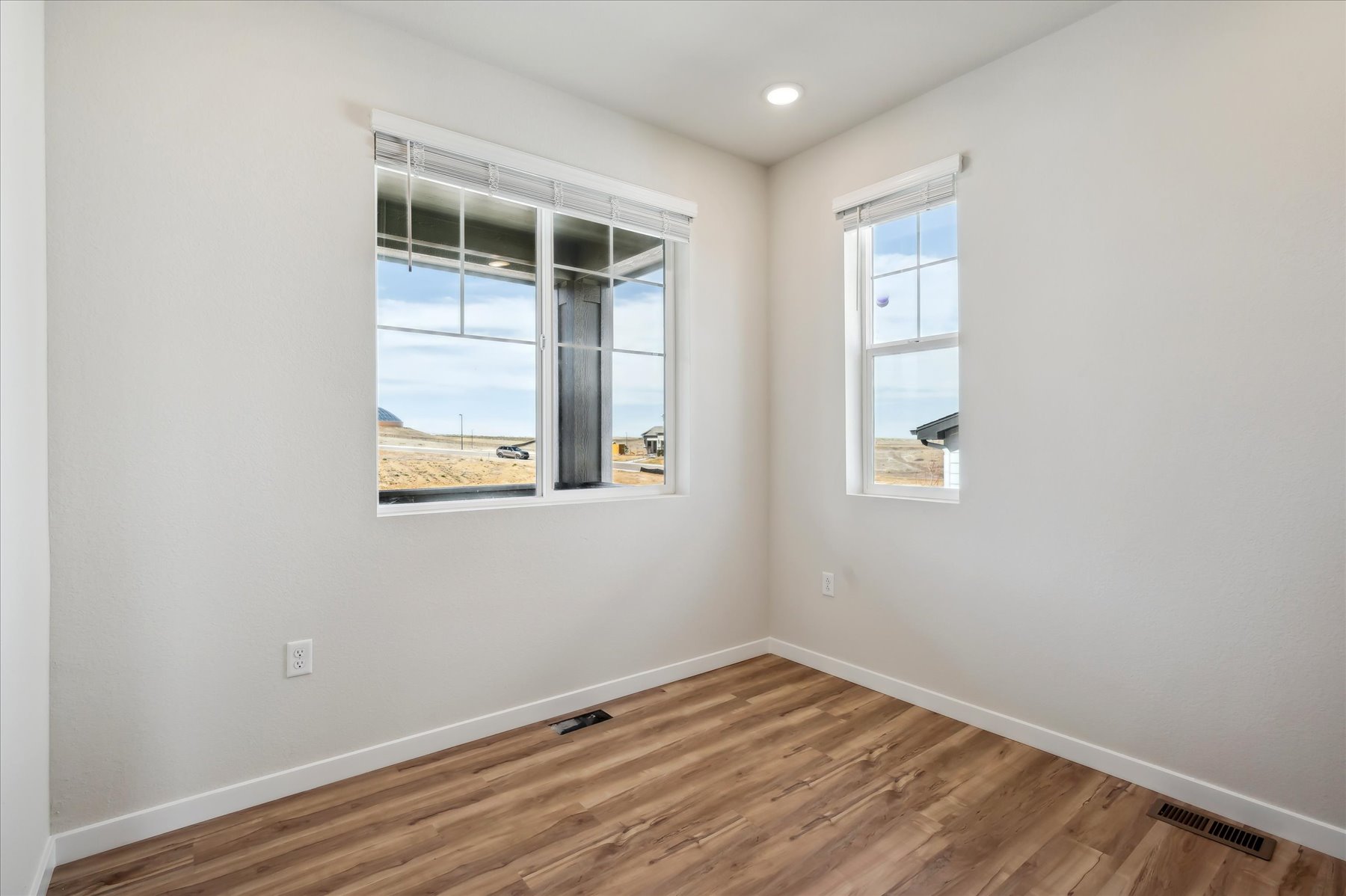 A room with a wood floor and a window with a view of the ocean.