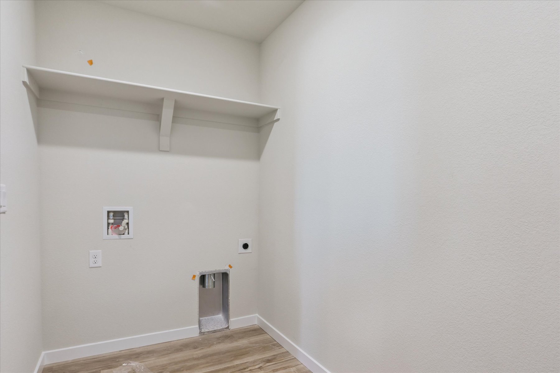A white room with a wood floor and a metal trash can.