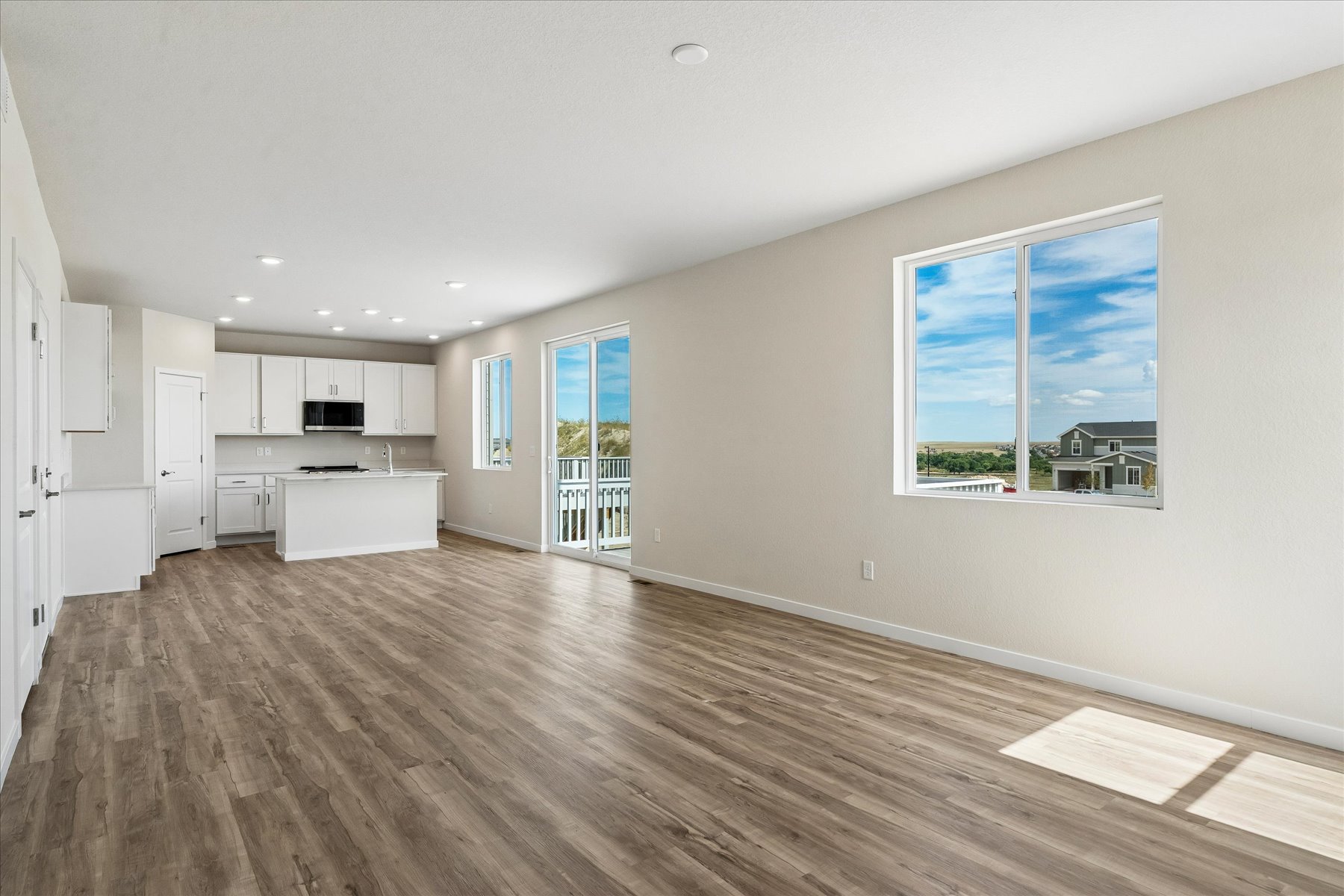 A large empty room with a wood floor and a large window.