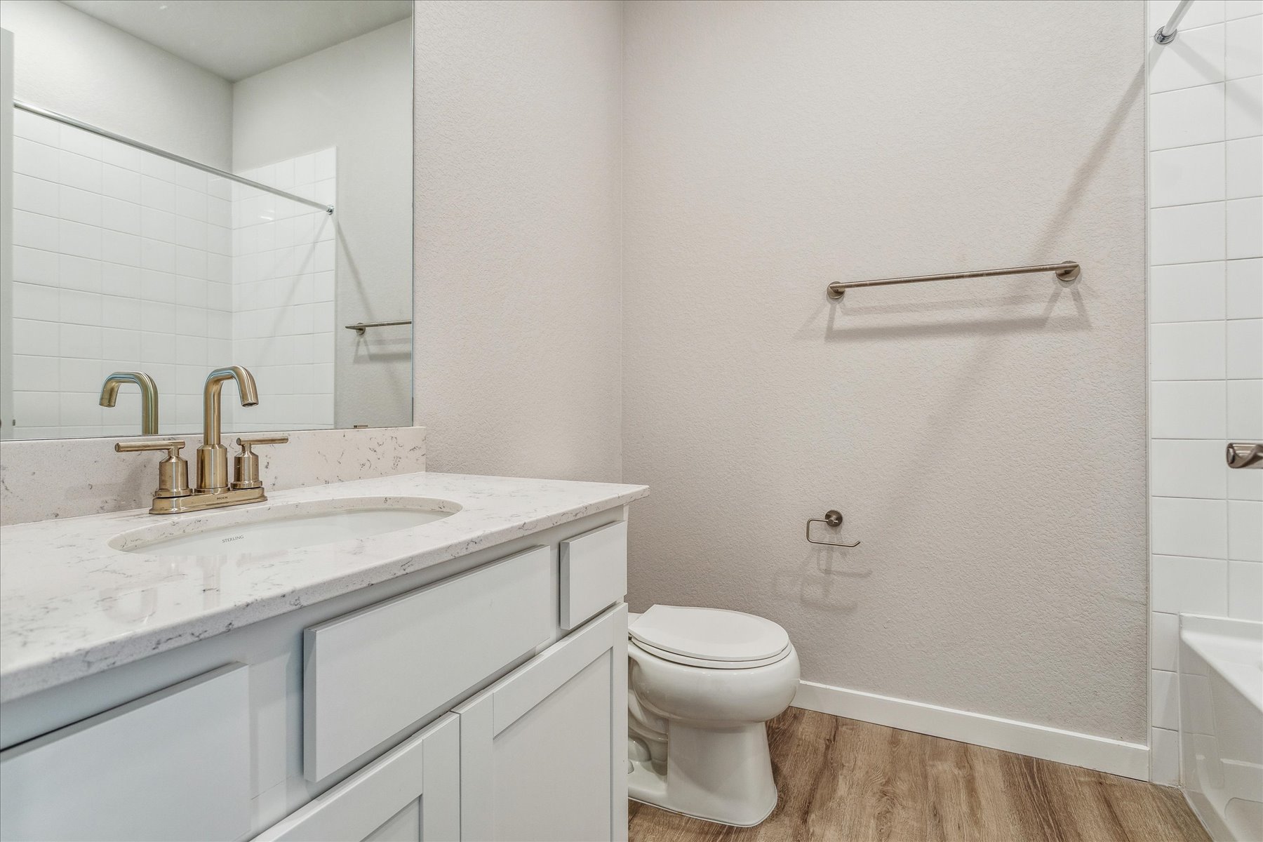 A bathroom with a sink toilet and mirror.
