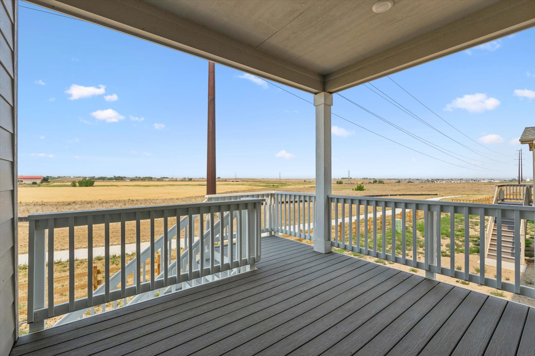 A wooden deck with a railing and a field in the background.
