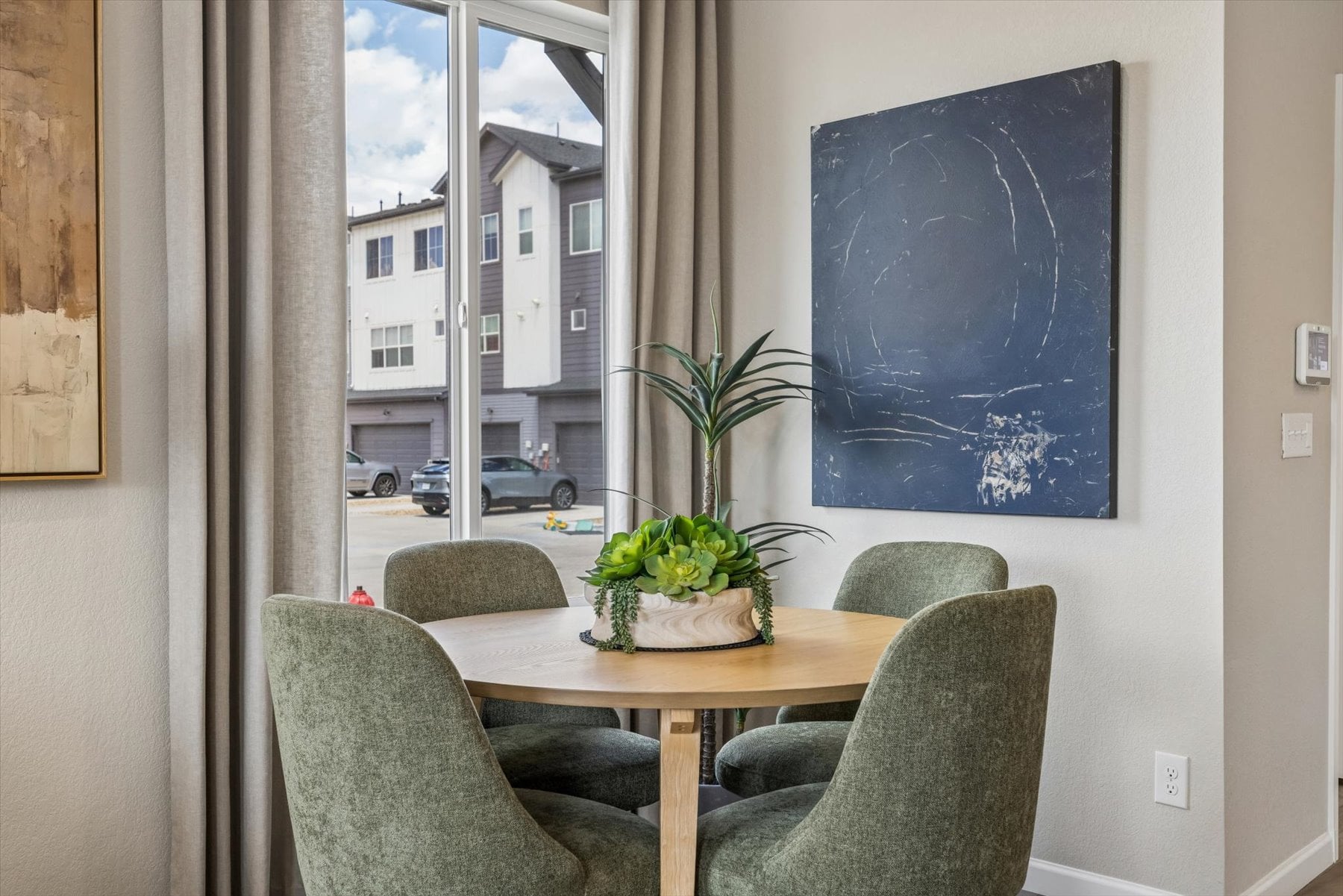 A table with chairs and a plant on it in a room with a window.
