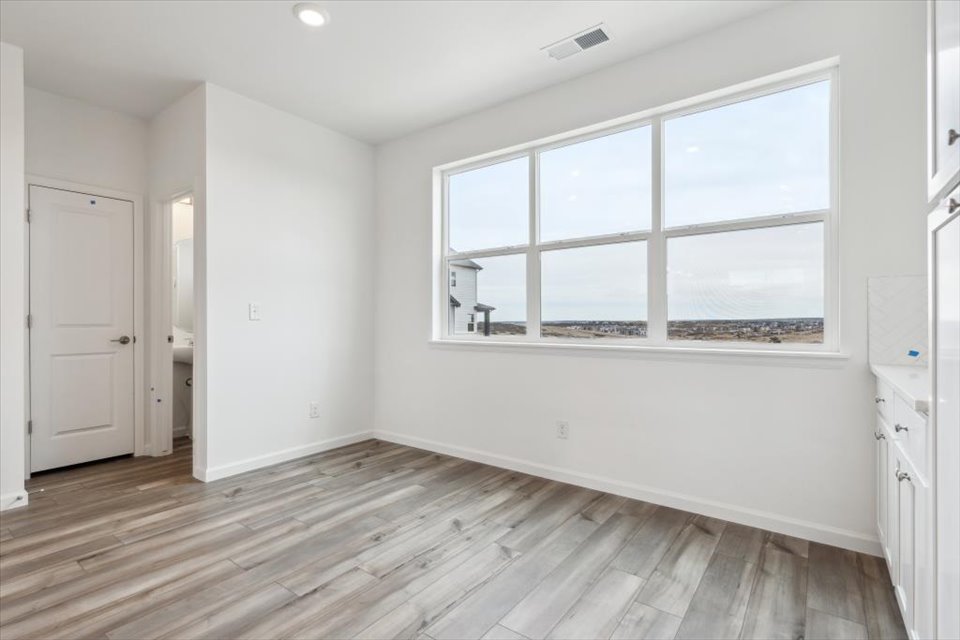 A room with a wood floor and a window with a view of the city.