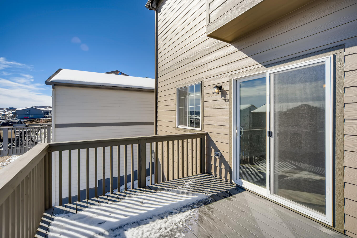 A deck with a glass door and a deck with a view of the ocean and a building.