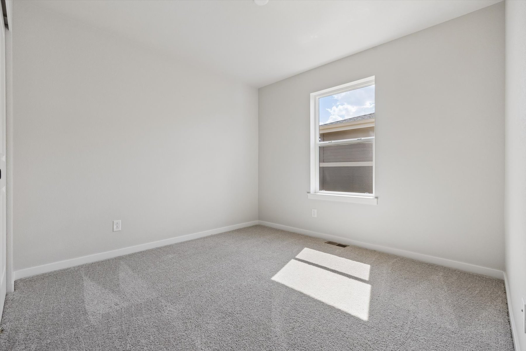 A room with a window and a rug in it.