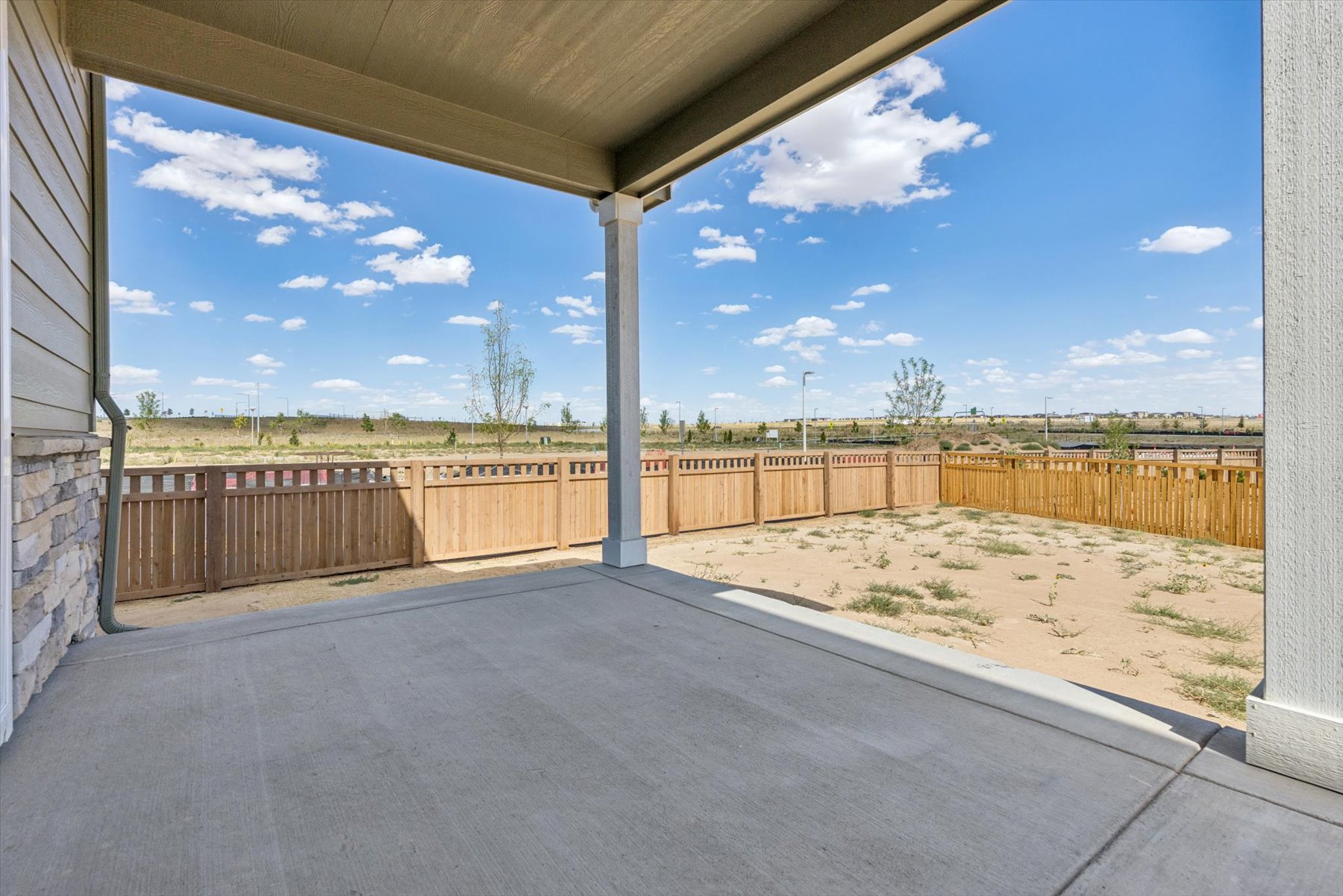 A concrete walkway with a fence and a wood fence.