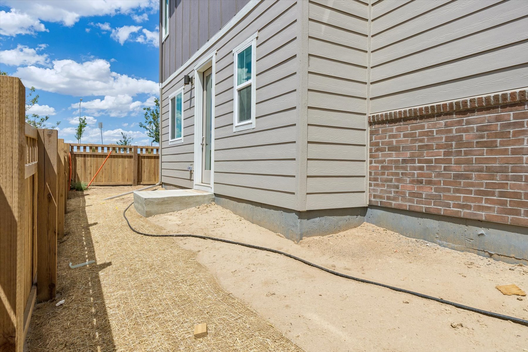 A house with a fence and a dirt yard.