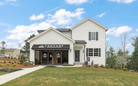 A white building with a sign on it with Southfork Ranch in the background.