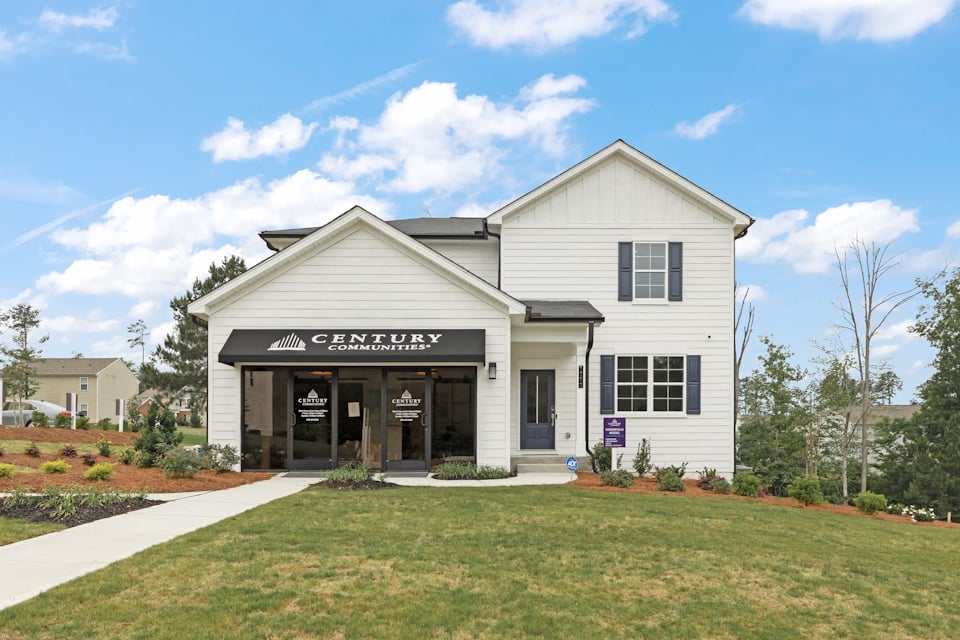 A white building with a sign on it with Southfork Ranch in the background.