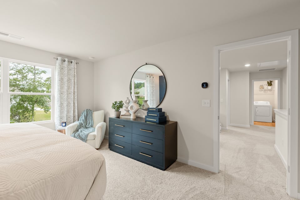 A bedroom with a bed and a mirror.